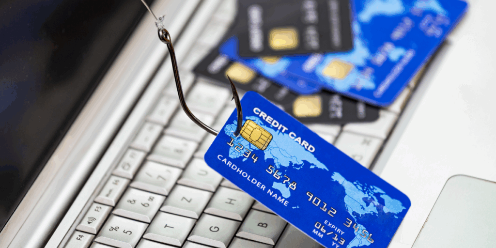 Carta di credito agganciata da un amo da pesca su una tastiera, simbolo visivo di un attacco di phishing e furto di dati tramite social engineering.